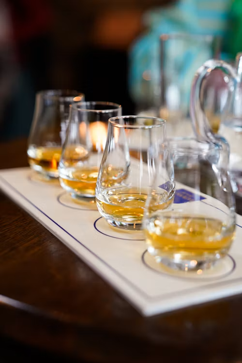 Four tasting glasses of whiskey lined up on a tasting board at a bar