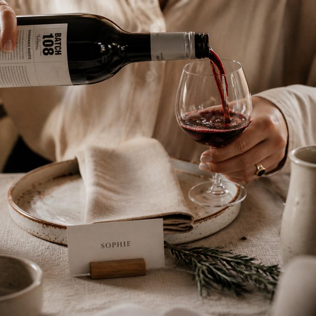 Wine poured beside a linen napkin, ceramic plate and letterpress place card